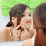 Young teenage woman with pimple