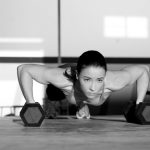 Gym woman push-up strength pushup with dumbbell